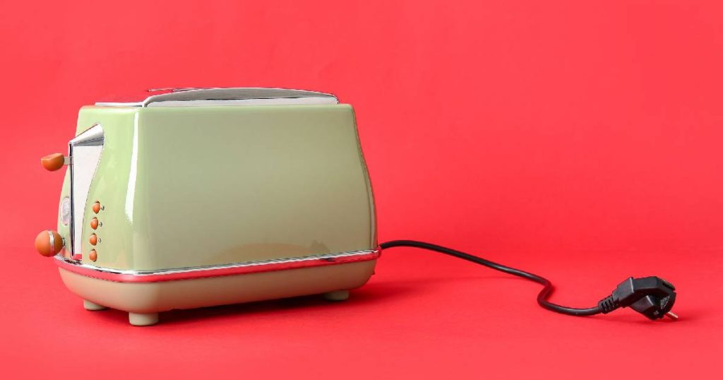 Een moderne retro toaster met vintage design, een gedempt groene kleur en houtlook knopjes tegen een knalrode achtergrond. Een prachtige aanvulling op een speelse vintage keuken met het nodige moderne comfort. 