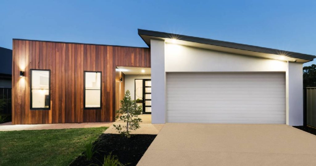 Een nieuwbouwwoning met verspringend lessenaarsdak, houten gevel en witte garage.