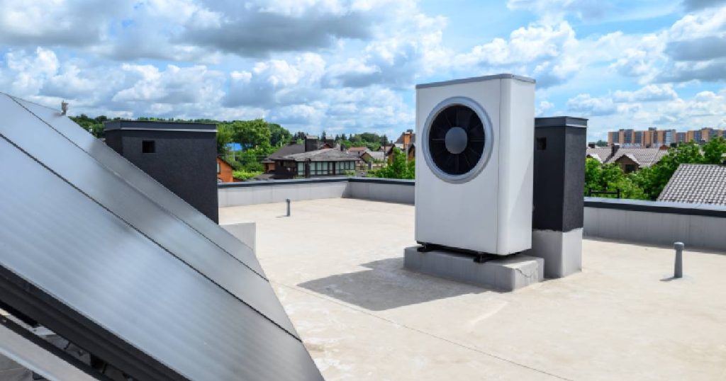 Een plat dak met de buitenunit van een airconditioning systeem of lucht-lucht warmtepomp en een installatie met zonnepanelen.